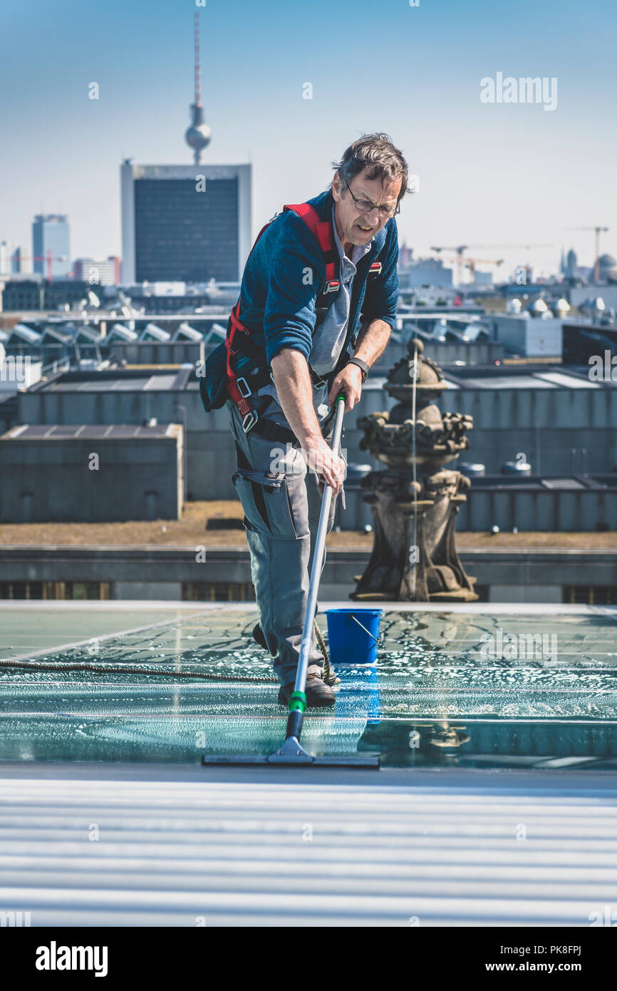 Un homme nettoie les fenêtres de toit sur le dessus du bâtiment du Reichstag dans la capitale allemande Berlin. Banque D'Images