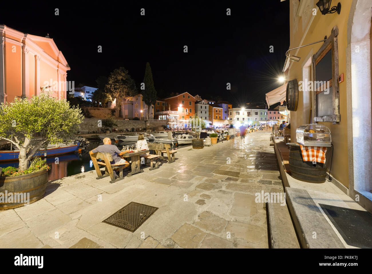 Les gens sont assis dans les restaurants dans le port illuminé dans la vieille ville de la station balnéaire de nuit Veli Lošinj, Lošinj, la baie de Kvarner, Croatie Banque D'Images