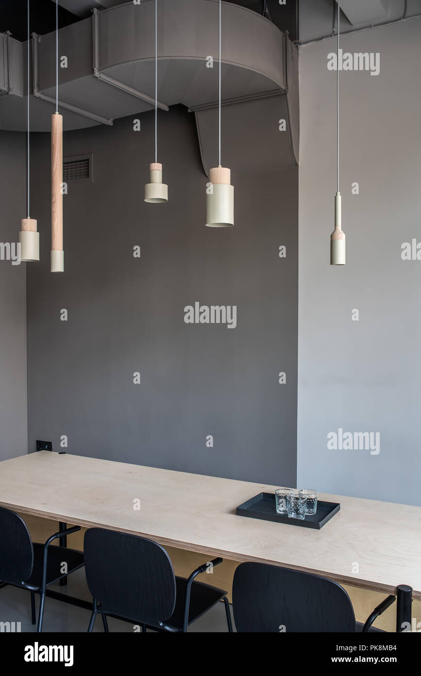 Salle de réunion élégante dans un bureau dans un style loft avec des murs gris. Il y a une grande table en bois avec bac noir avec des lunettes, trois chaises, différents Banque D'Images