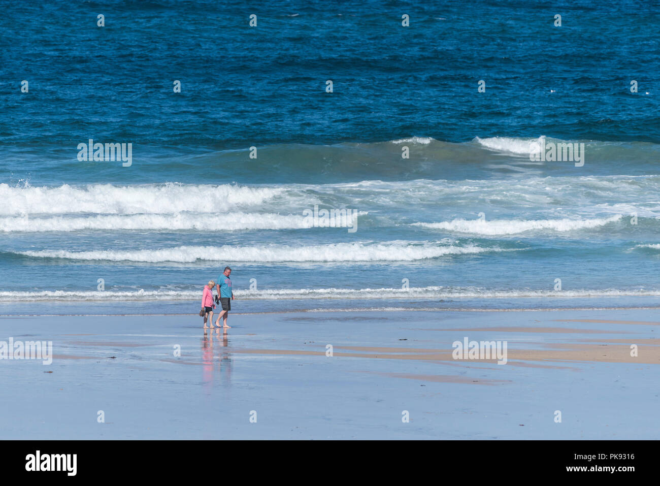 Un couple en vacances de marche pieds nus le long du rivage à Fistral Beach à Newquay Cornwall. Banque D'Images