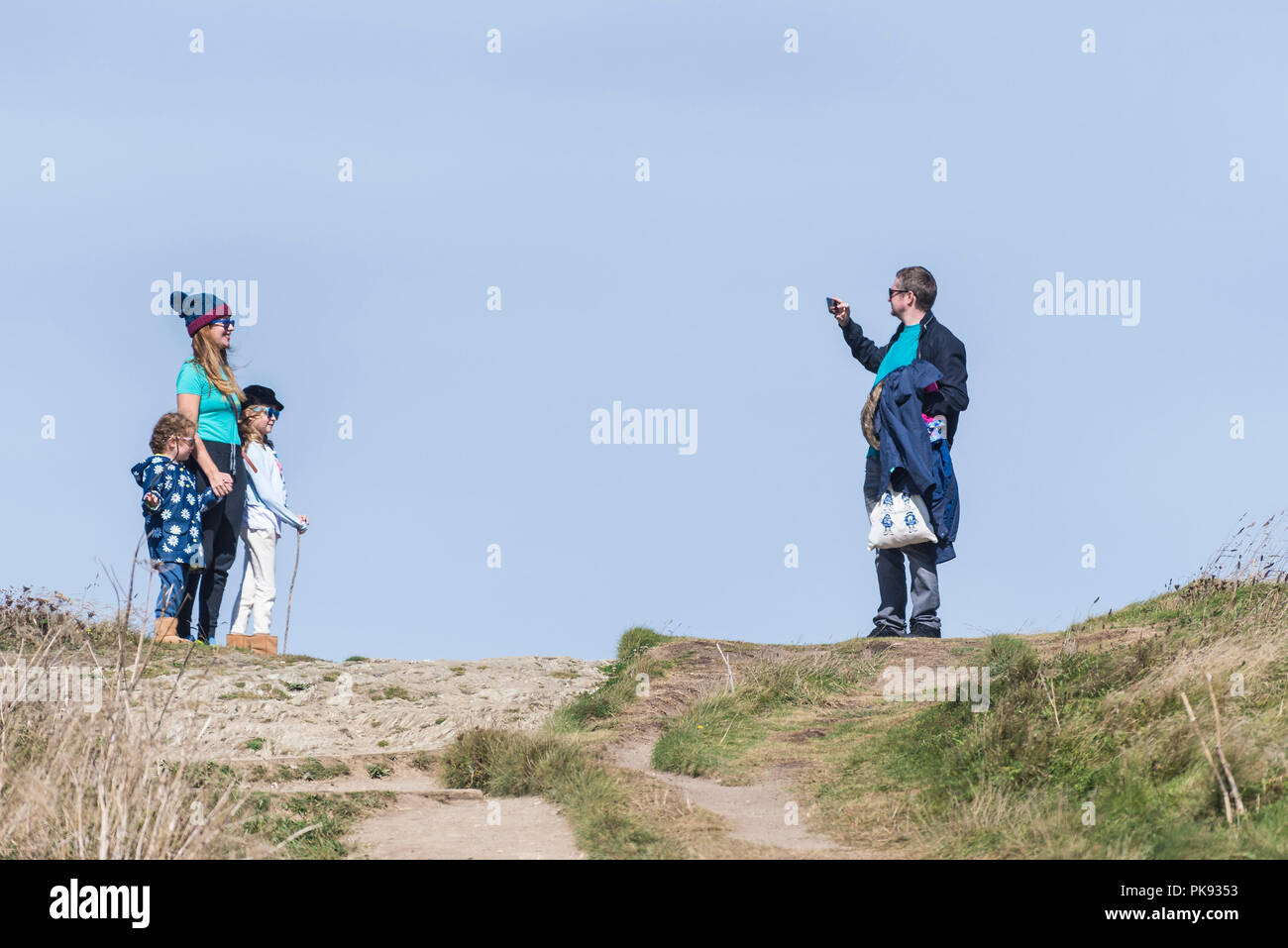 Un père prenant une photo d'une mère et de ses filles en vacances de marche à Towan Head à Newquay Cornwall. Banque D'Images