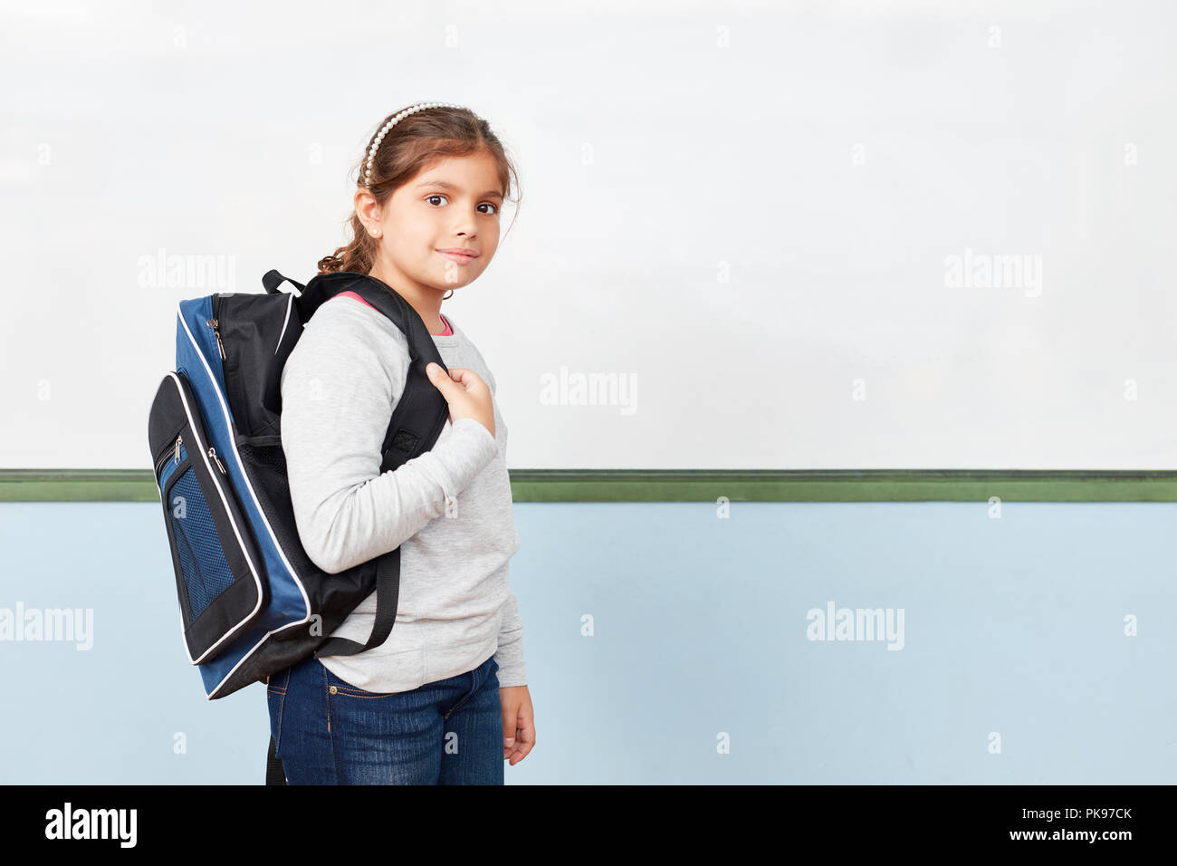Happy girl comme école-boy avec cartables dans une école en face du tableau blanc Banque D'Images