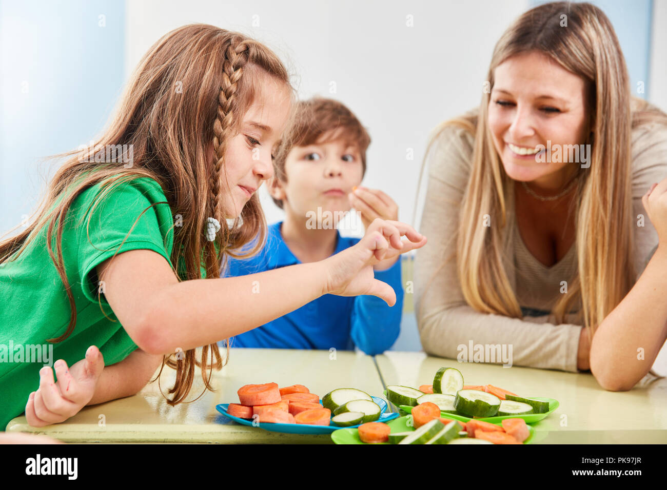 Les enfants dans la cafétéria de l'école élémentaire manger des légumes en collation Banque D'Images