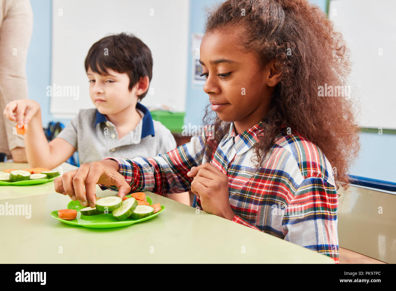 La fille est de manger des légumes sains comme collation collation dans la cafétéria de l'école Banque D'Images