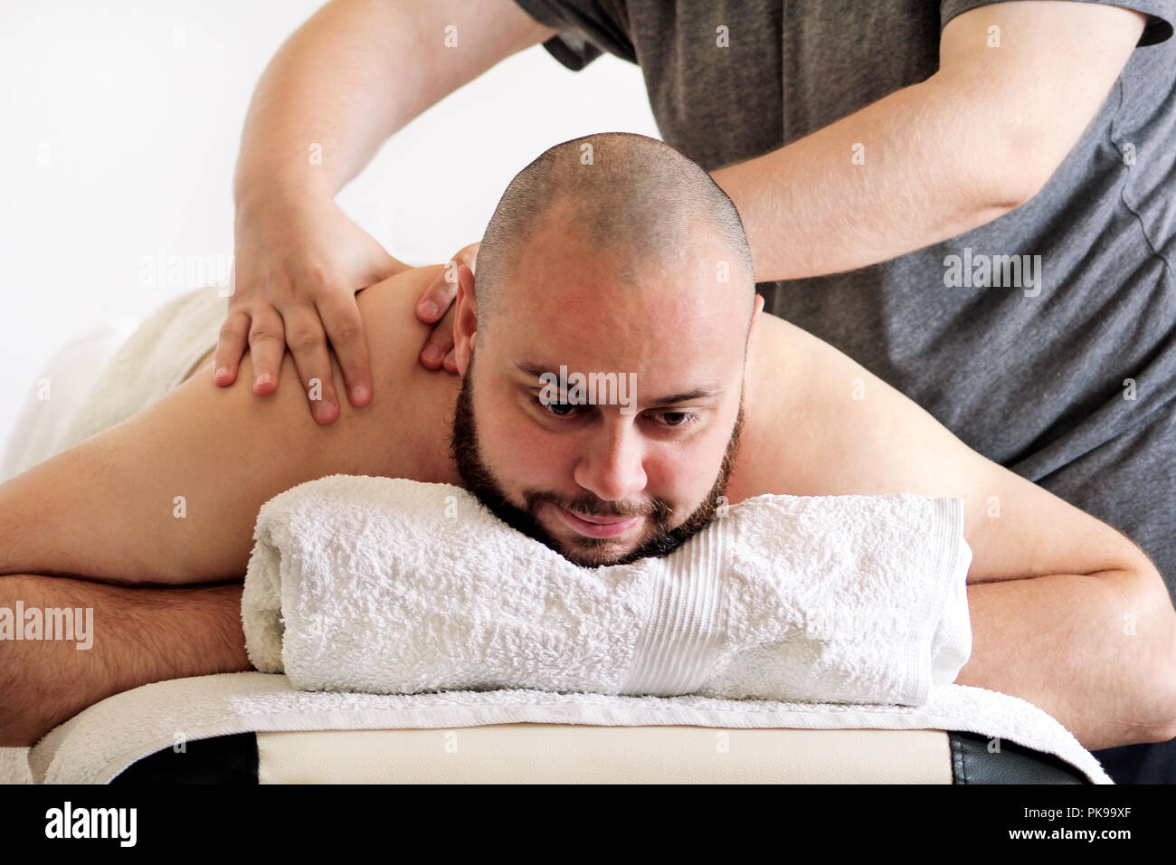 Studio de massage. Massage sportif. Massothérapeute masser les épaules d'un athlète masculin, le travail avec les muscles du cou. Les soins du corps. Massage homme. Banque D'Images
