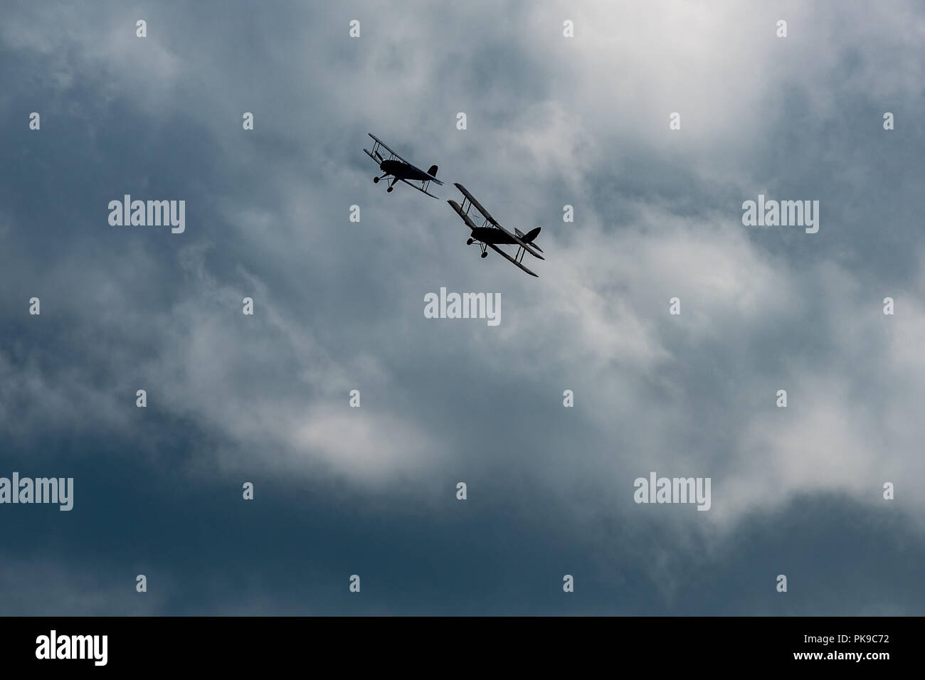 Tronçonneur Jungmann Bu 131 et de Havilland DH82 Tiger Moth biplans silhouetté contre un lourd ciel août lors d'un affichage de l'air Banque D'Images