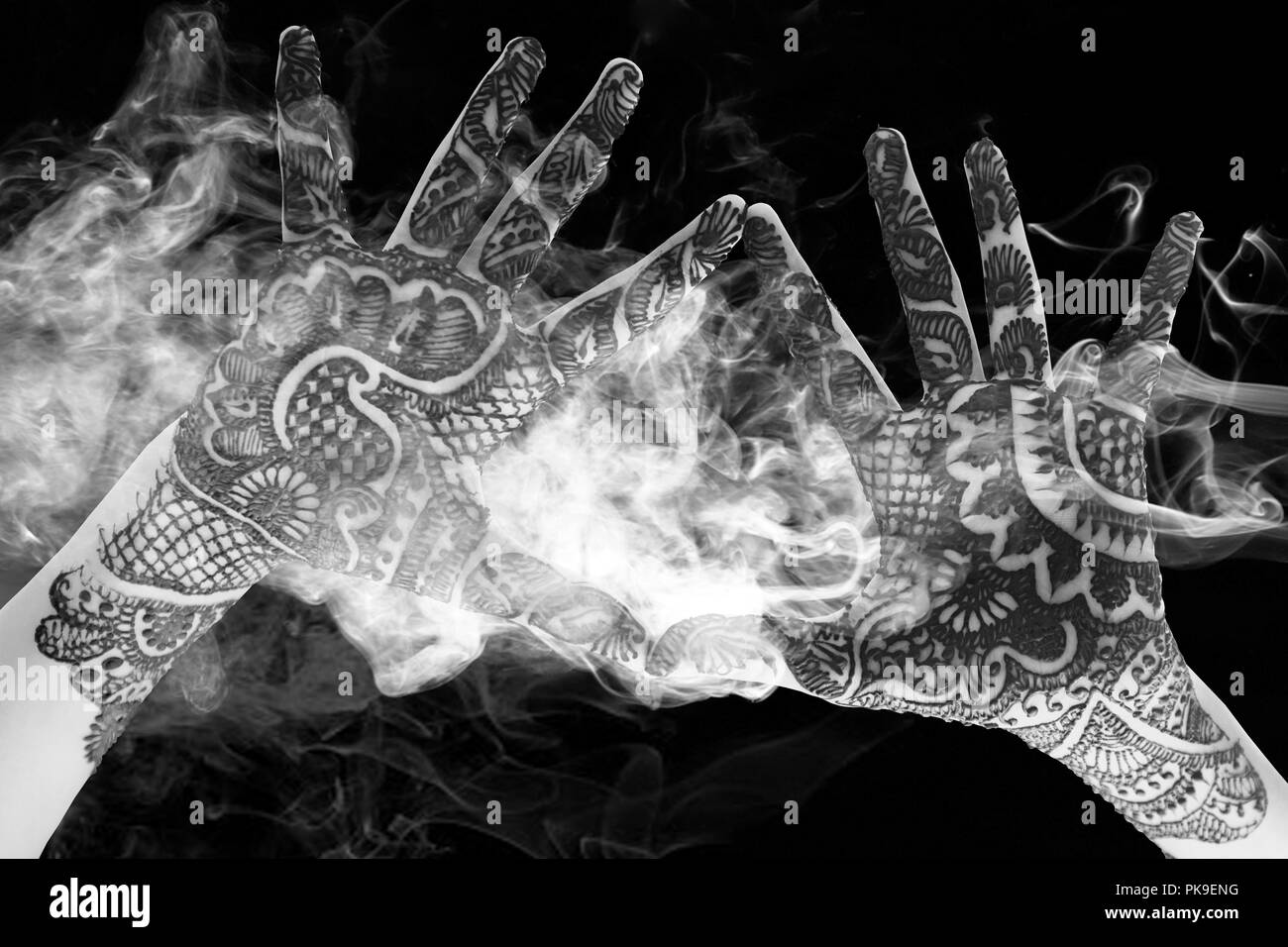 Le noir et blanc des mains ensemble pour montrer le beau tatouage au henné à l'ouvrir les mains et les bras avec de la fumée et de la lumière Banque D'Images