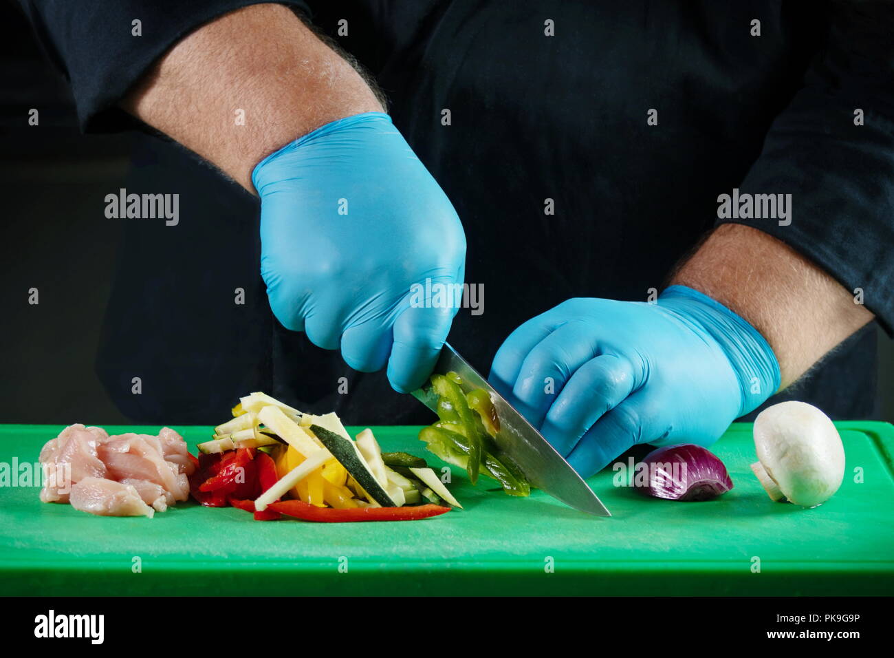 Les mains gantées du chef à couper les aliments et de les préparer pour la cuisson une recette spécifique Banque D'Images