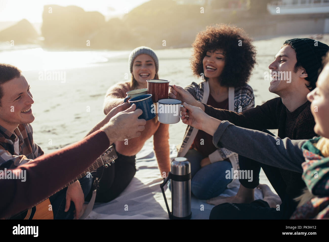 Groupe de jeunes multi-ethnique toasting tasses à café sur la plage. Groupe d'amis de passer du temps ensemble à la plage, le café. Banque D'Images