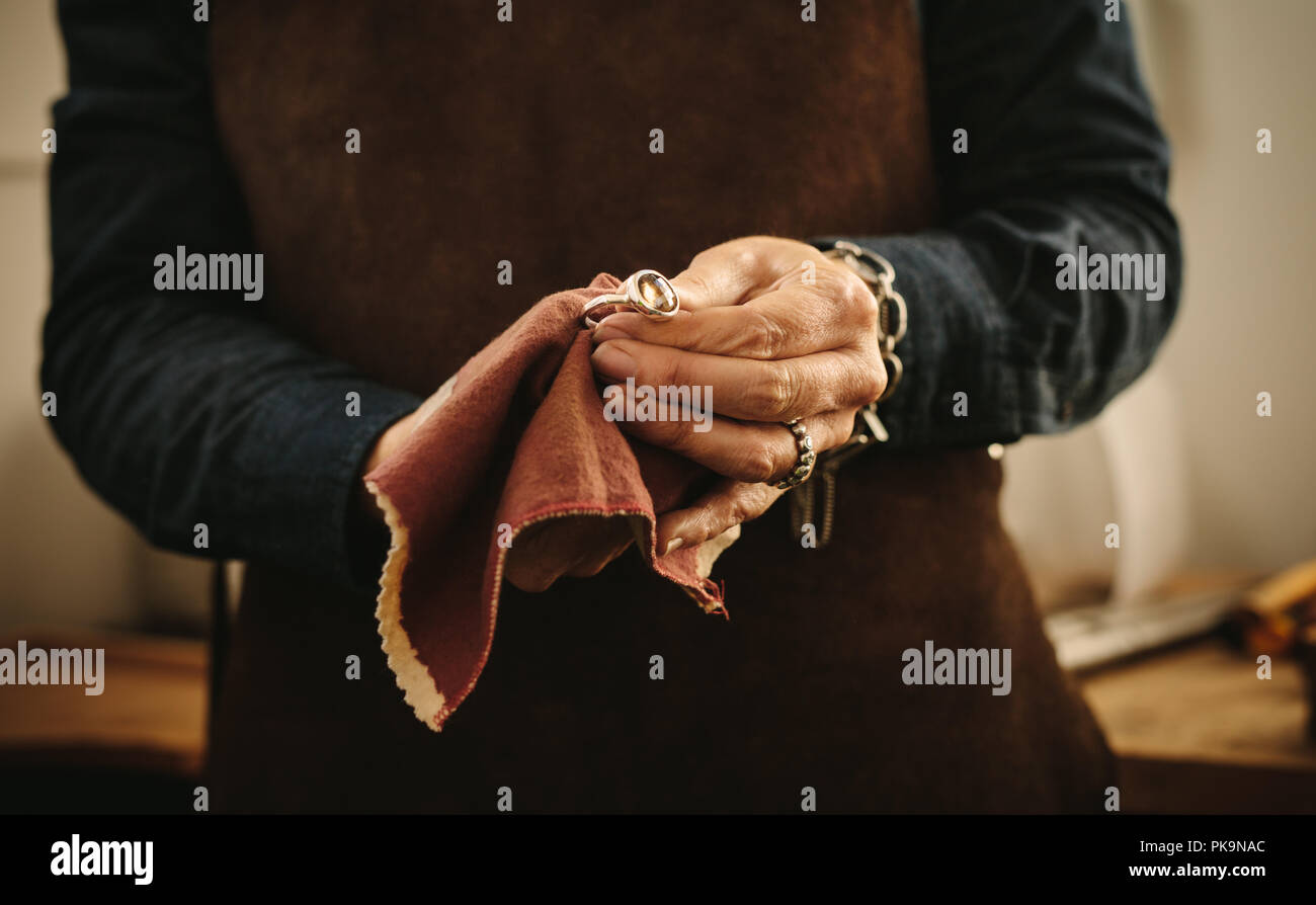 Mains de femme argent polissage bijouterie bijoux à l'ancienne avec un  chiffon. Bijoux bague un essuyage avec un chiffon à son atelier Photo Stock  - Alamy