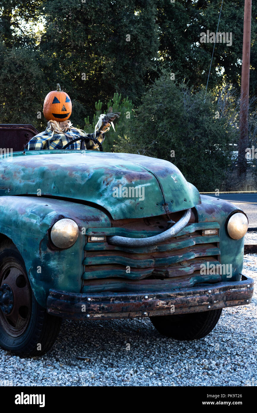 Accueillant, souriant, heureux, fun friendly tête de citrouille épouvantail conduisant un vieux camion à un halloween fête des récoltes à l'automne Banque D'Images