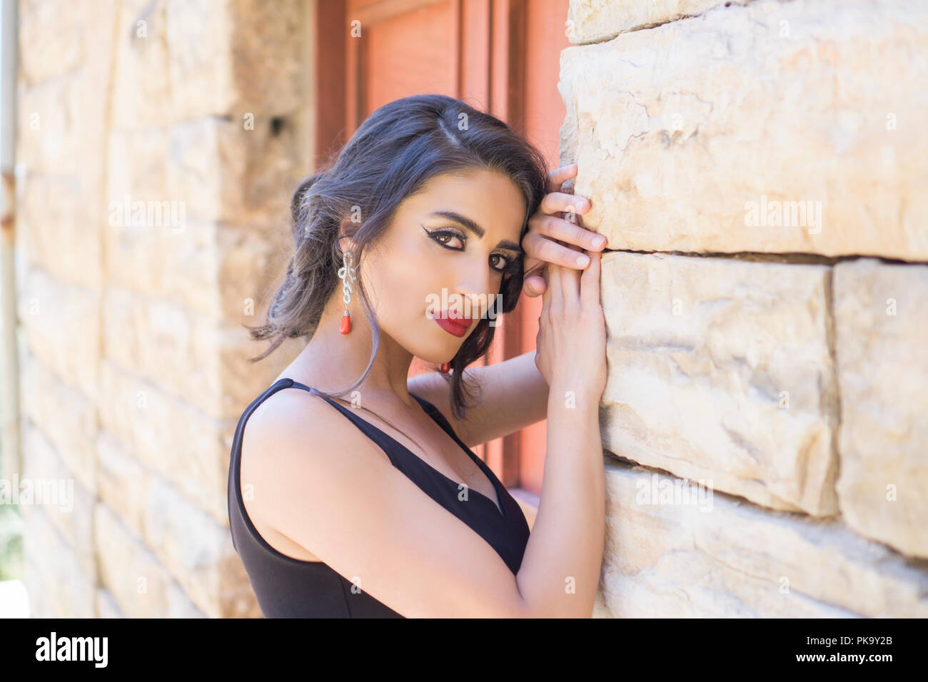 Beautiful woman leaning against wall outdoors Banque D'Images