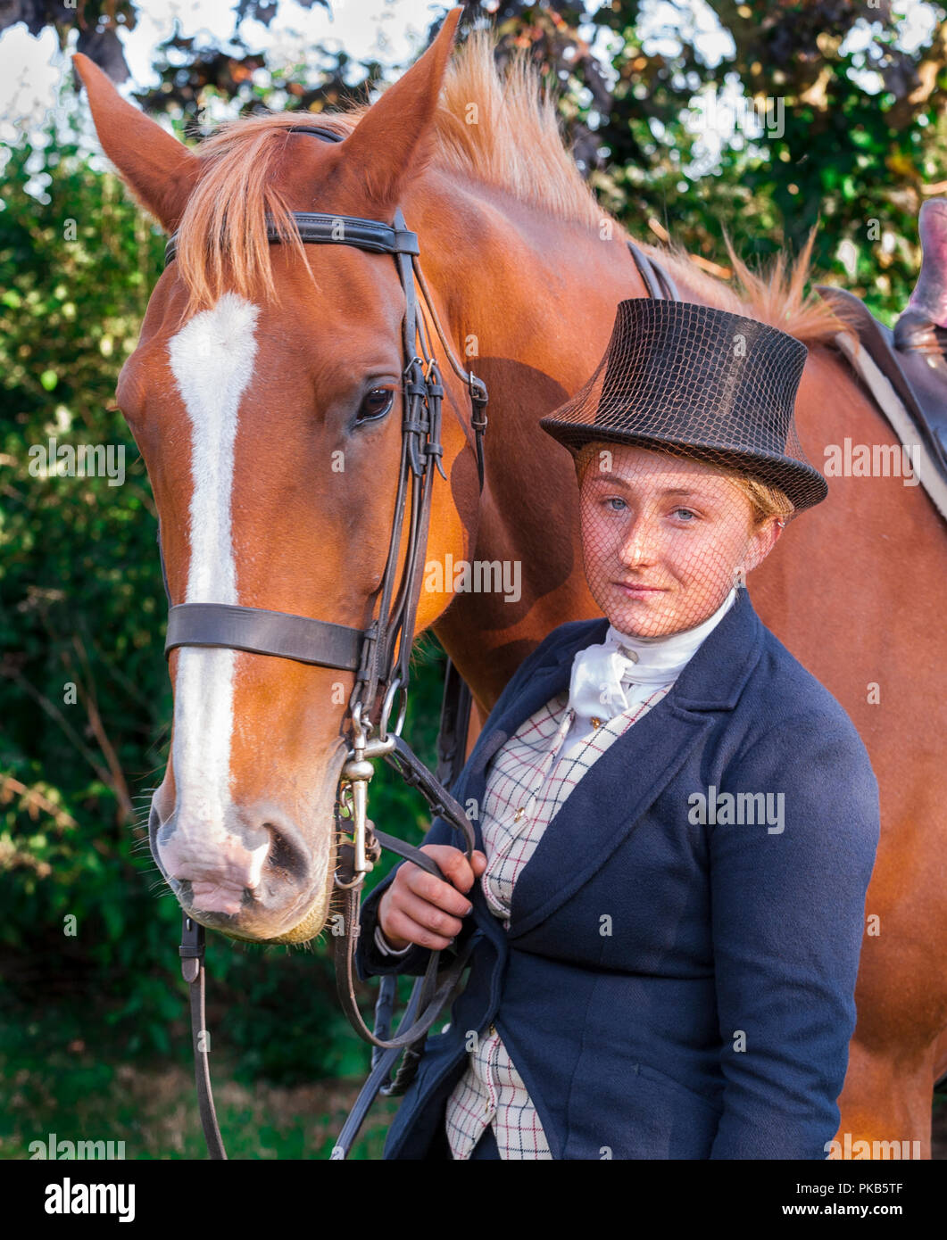 Une jeune femme se tenait elegent avec son cheval habillé en équitation  traditionnelle top hat et voile intégral Photo Stock - Alamy
