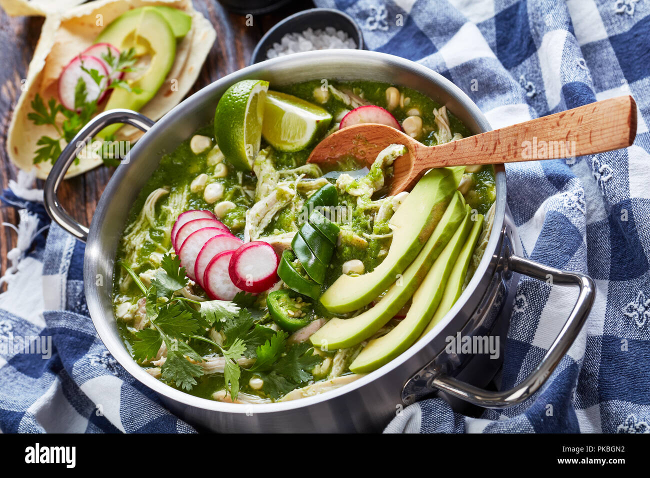 Pozole vert dans une casserole en métal - ragoût mexicain rempli de viande et déchiqueté dans un cadre chaleureux hominy bouillon chili vert garni de tranches de radis, cilant Banque D'Images