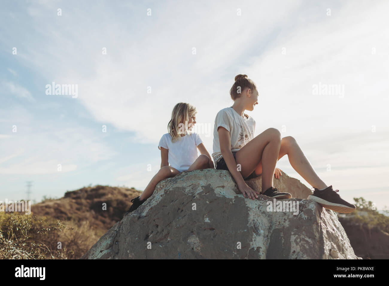Deux jeunes filles s'asseoir sur un rocher à la recherche ; Los Angeles, Californie, États-Unis d'Amérique Banque D'Images