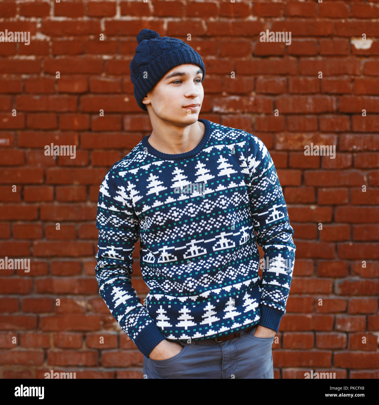 L'homme en tricot de pull-over chaud avec des motifs de Noël et hat  standing près de red brick wall Photo Stock - Alamy