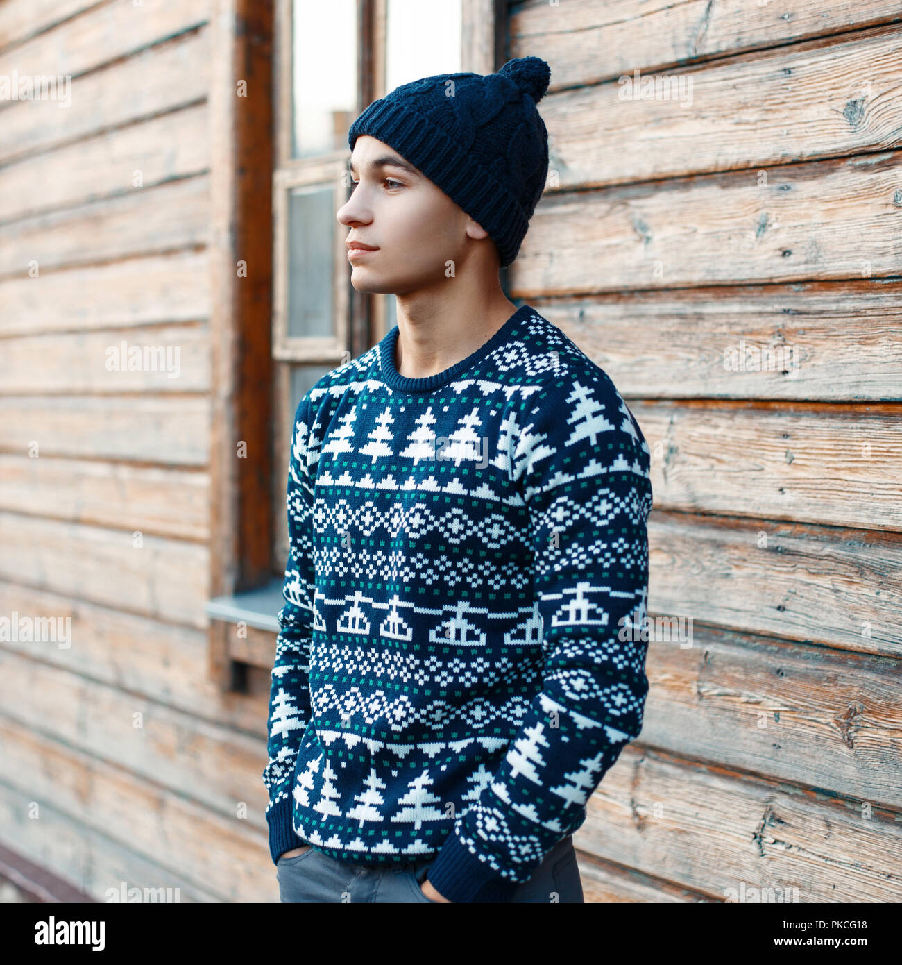 Jeune beau gars en hiver chandail de Noël sur l'arrière-plan d'une maison  en bois. L'homme se reposant dans la campagne Photo Stock - Alamy