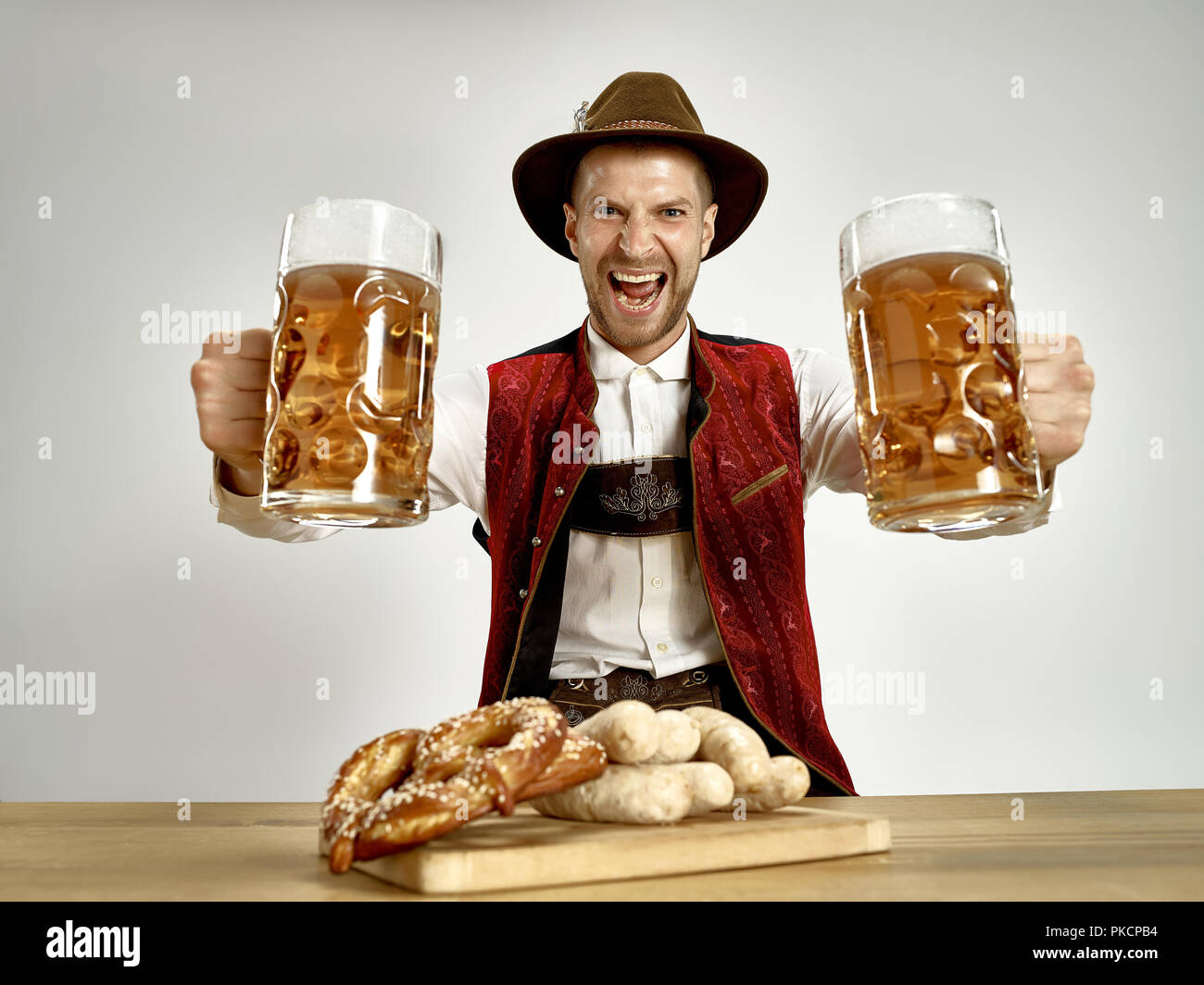 Allemagne, Berlin,. Le jeune happy smiling man with beer habillés en costume traditionnel bavarois ou autrichienne holding mug de bière au pub ou studio. La célébration, l'Oktoberfest, concept festival Banque D'Images