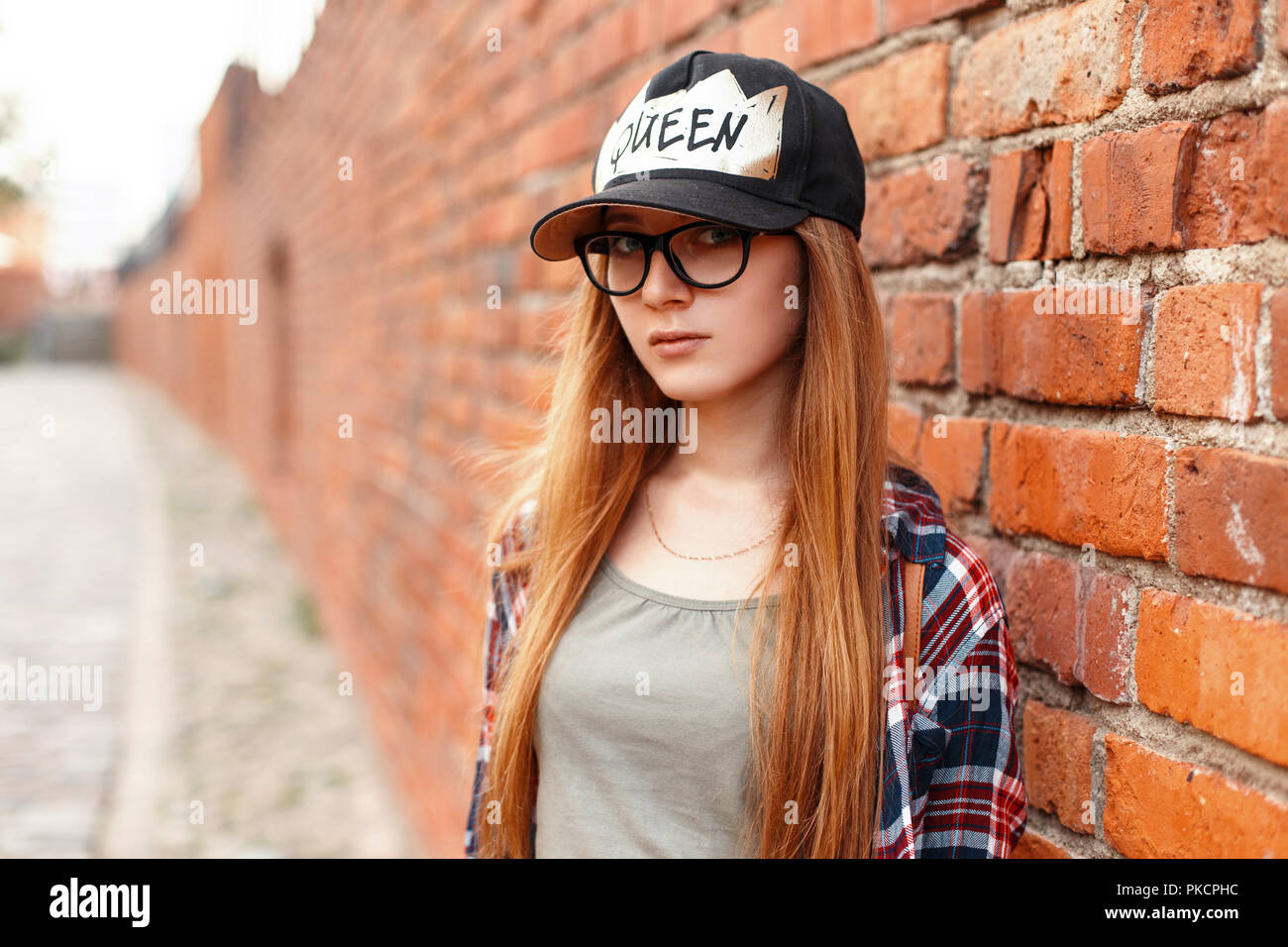 Assez élégant hipster femme avec des lunettes et un chapeau à proximité  d'un mur de brique rouge Photo Stock - Alamy
