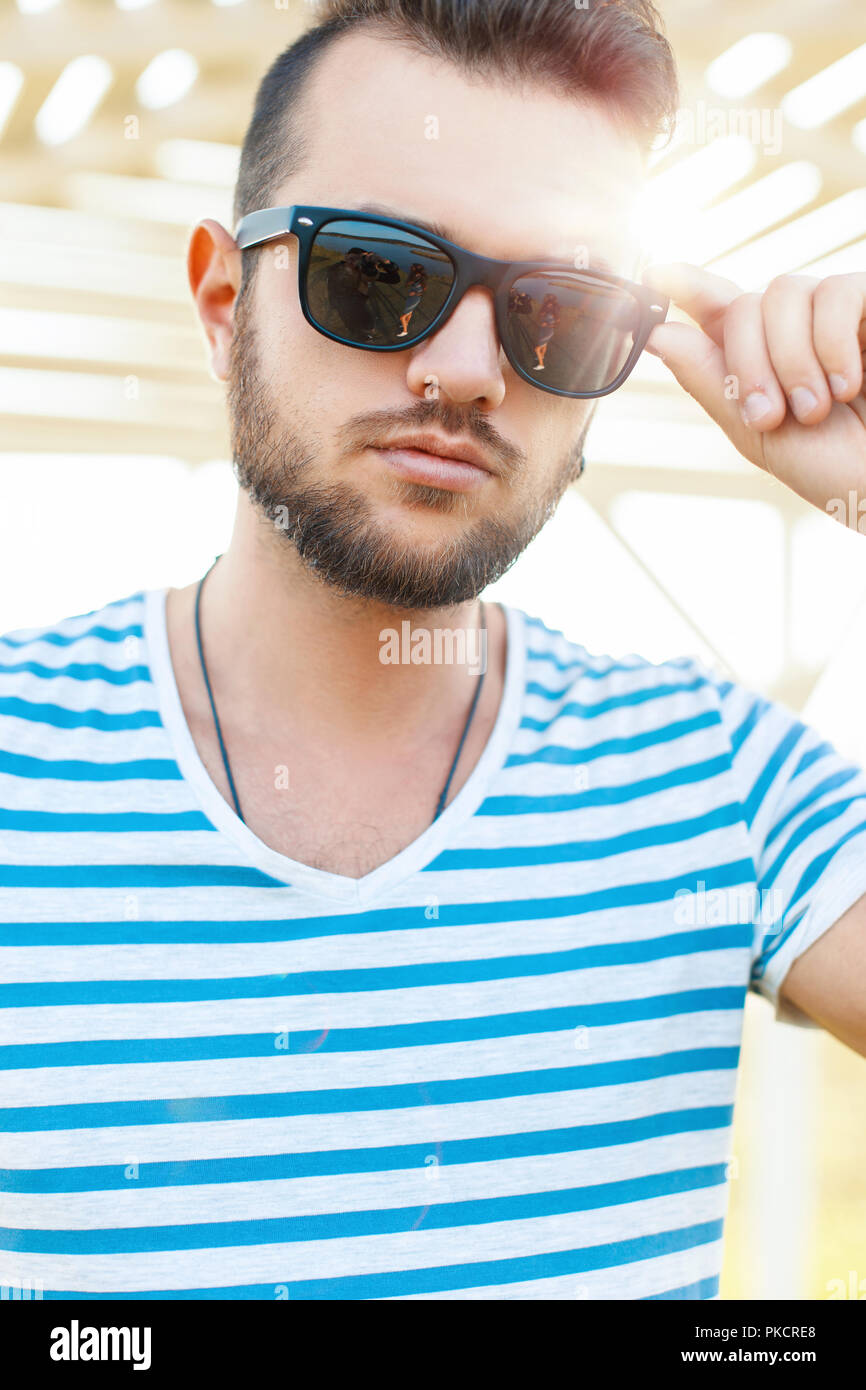 Hipster beau mec avec une barbe et avec des lunettes de soleil dans la  lumière du soleil sur la plage un jour d'été Photo Stock - Alamy