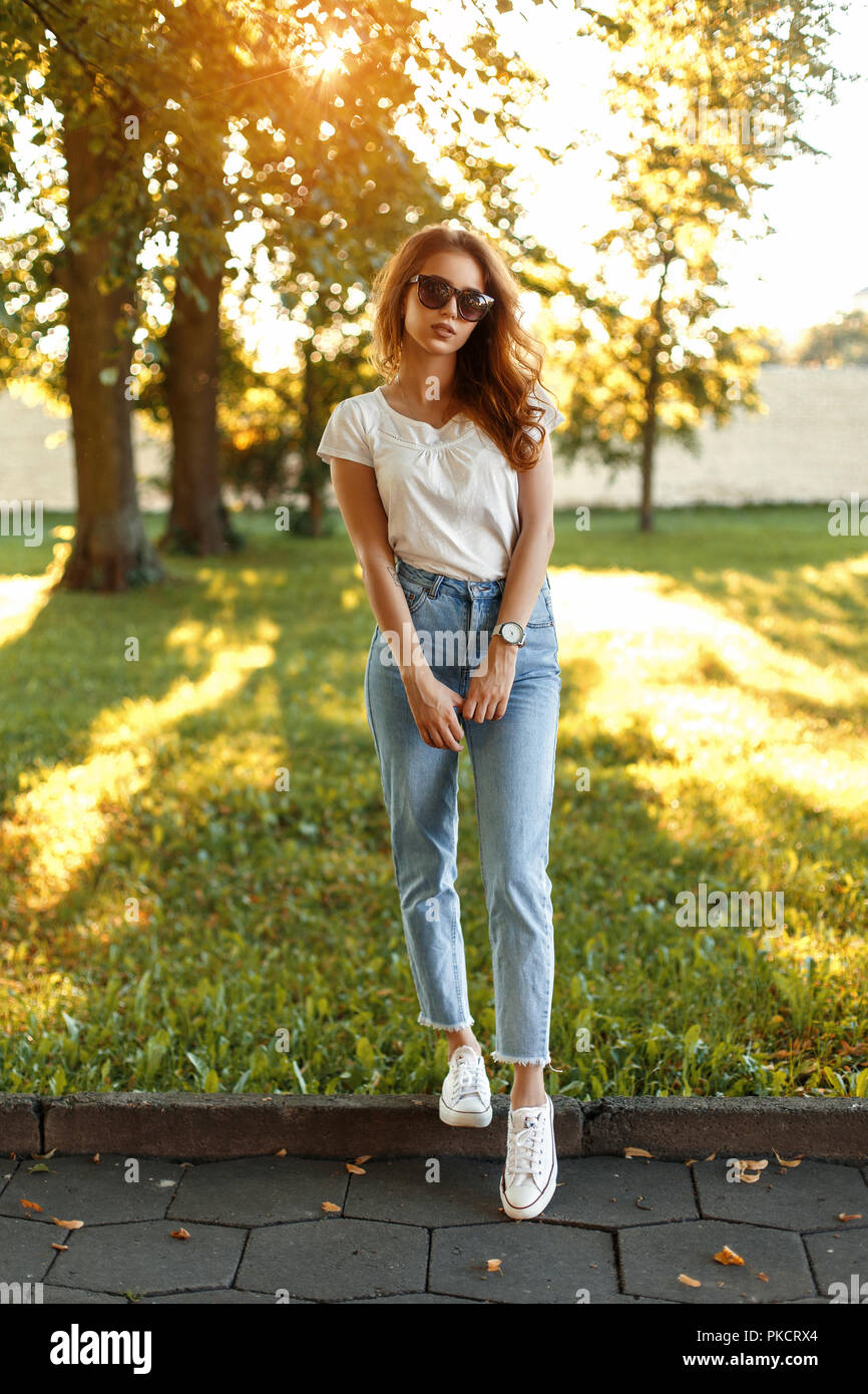 Belle fille élégante dans des vêtements à la mode se trouve dans le parc sur une journée ensoleillée Banque D'Images