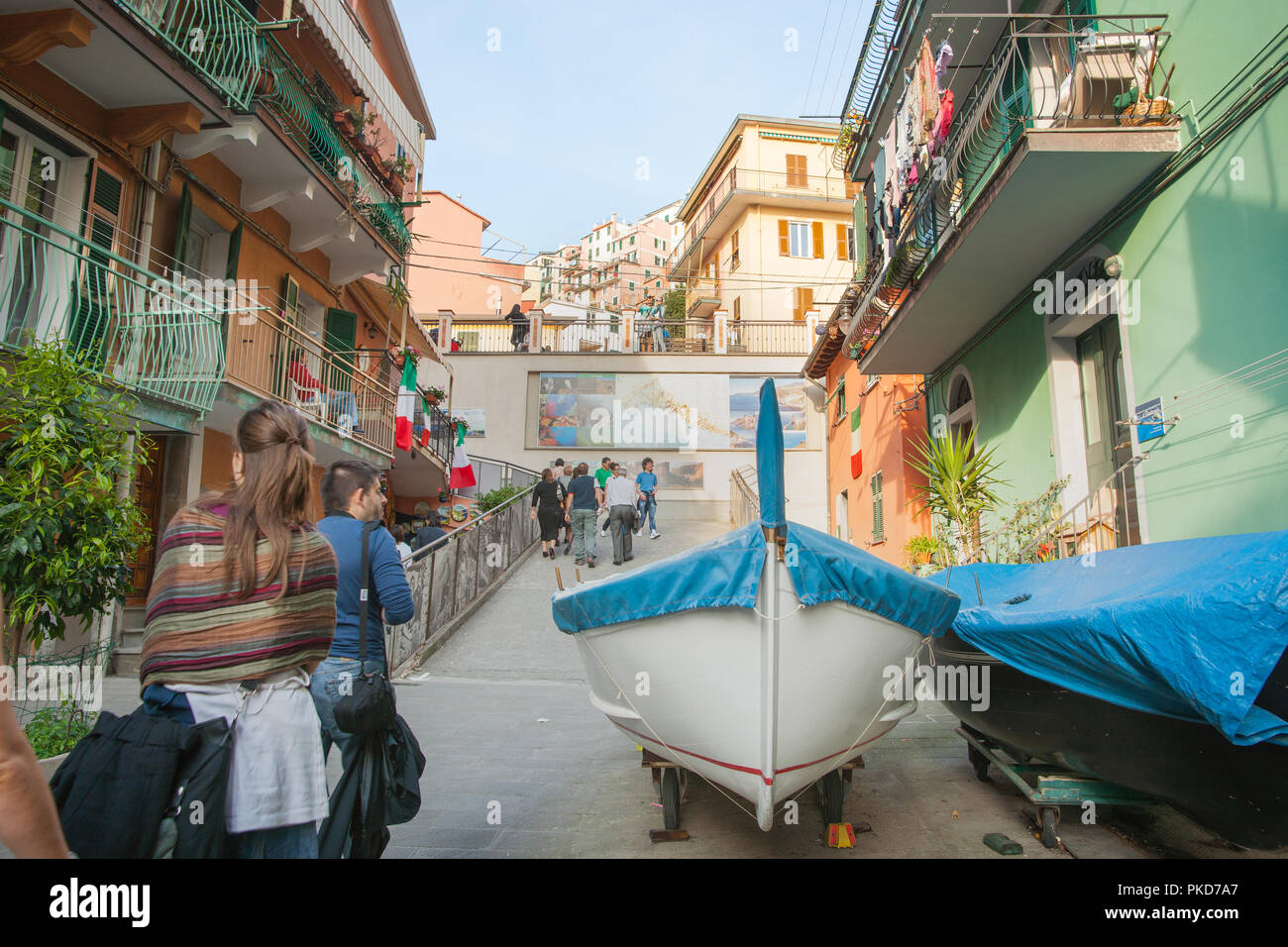 CINQUE TERRE, ITALIE - 25 avril 2011 ; bateaux tiré vers le haut dans une étroite rue du village en tant que touristes traversent à la recherche à l'architecture typique, boutiques et voile Banque D'Images