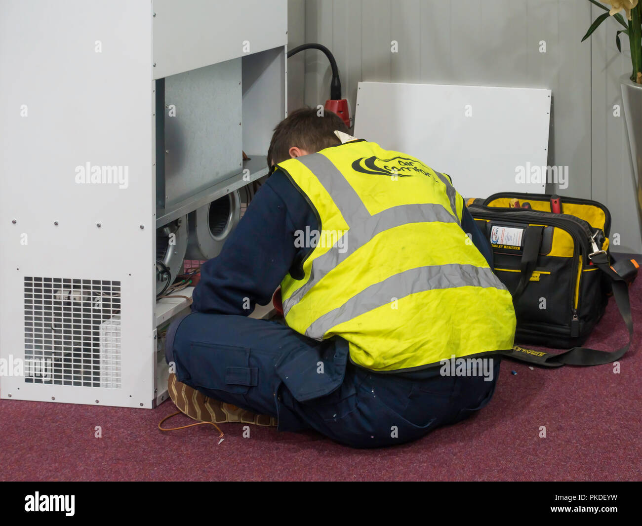 Technicien de faire une réparation sur place d'une unité de climatisation dans un local commercial Banque D'Images