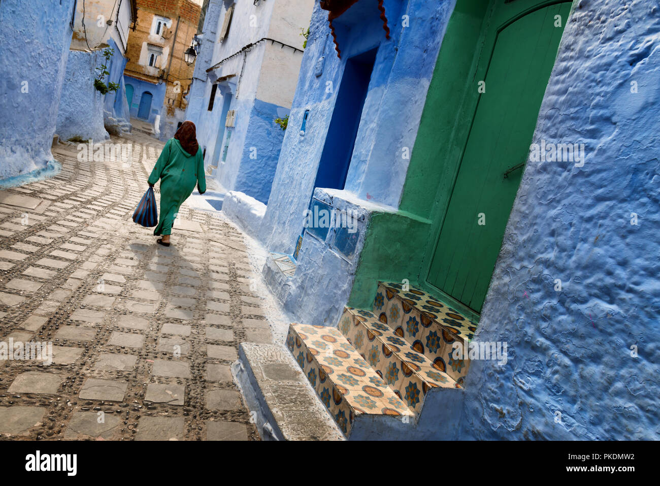 Un traditionnel habillé femme marocaine promenades dans la vieille ville (médina) de Chefchaouen au Maroc. Banque D'Images