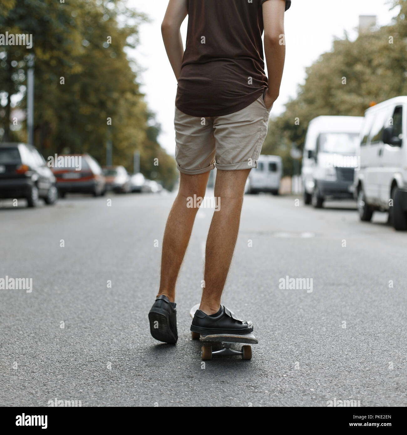Homme monté sur une planche à roulettes. Les jambes sur une planche à roulettes. Banque D'Images