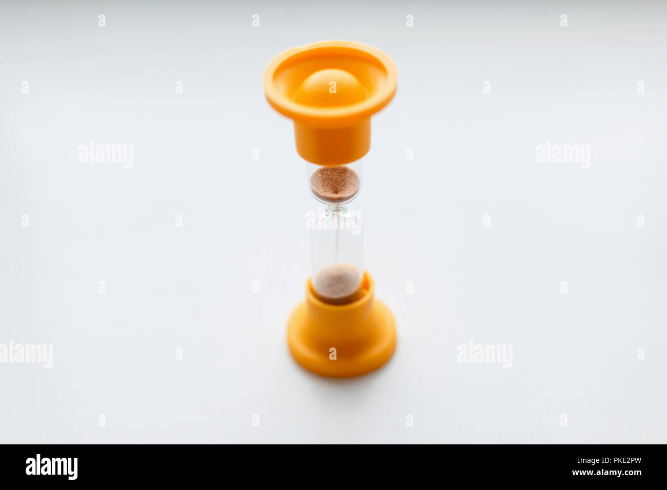 Sablier en plastique orange Vintage sur un fond blanc. Banque D'Images