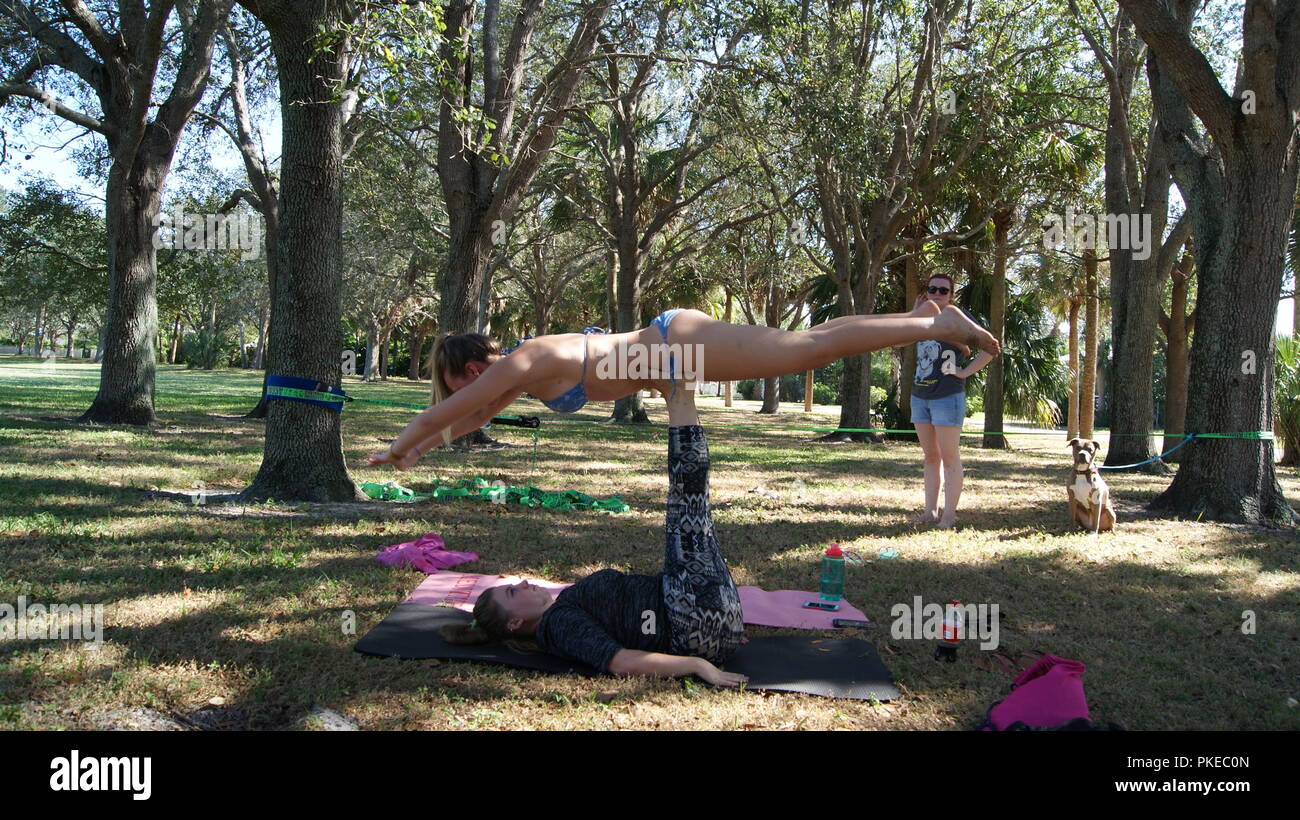 Les jeunes femmes de faire pratiquer le yoga acro sur un parc public en Floride, Jupiter, en Floride. USA - 17 juin 2017. Banque D'Images
