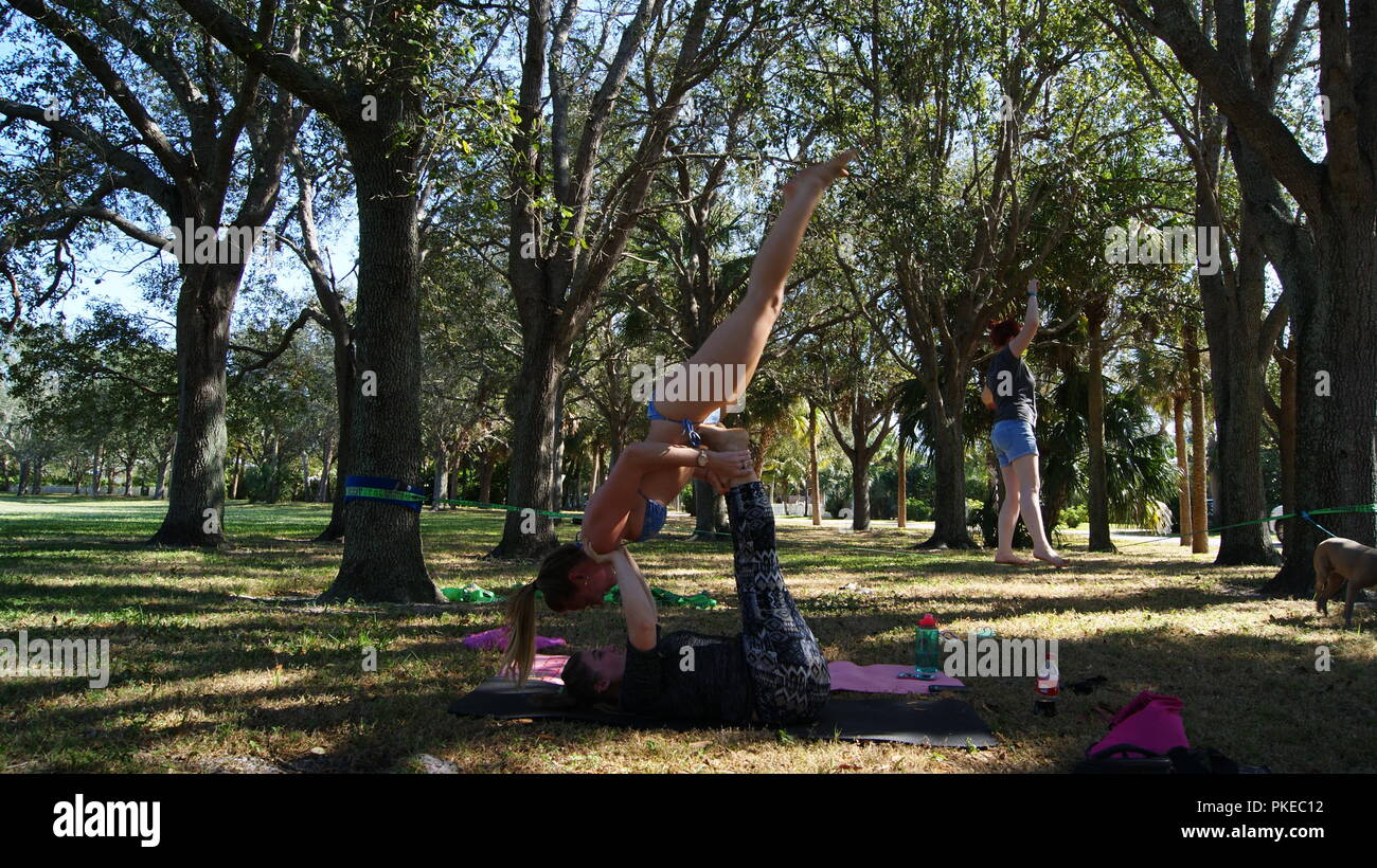 Les jeunes femmes de faire pratiquer le yoga acro sur un parc public en Floride, Jupiter, en Floride. USA - 17 juin 2017. Banque D'Images