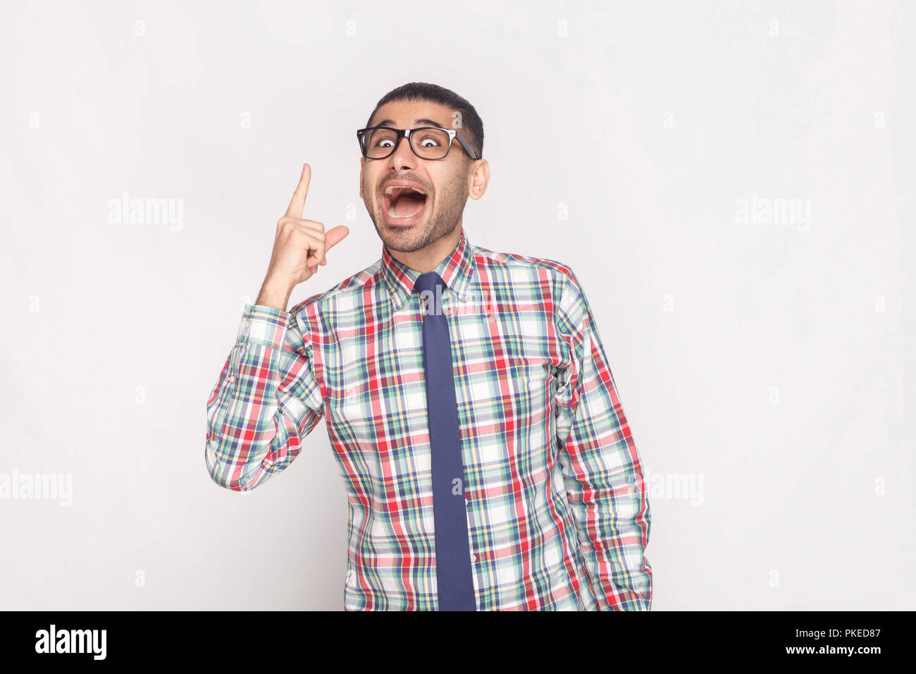 J'ai idée. Heureux surpris beau homme barbu en chemise à carreaux colorés, cravate bleue et lunettes noires et permanent à la caméra à l'INDO. Banque D'Images