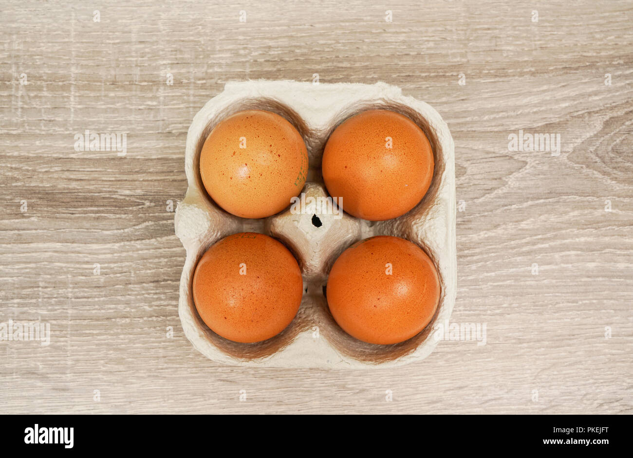 Quatre œufs dans une boîte en carton sur la table en bois Banque D'Images