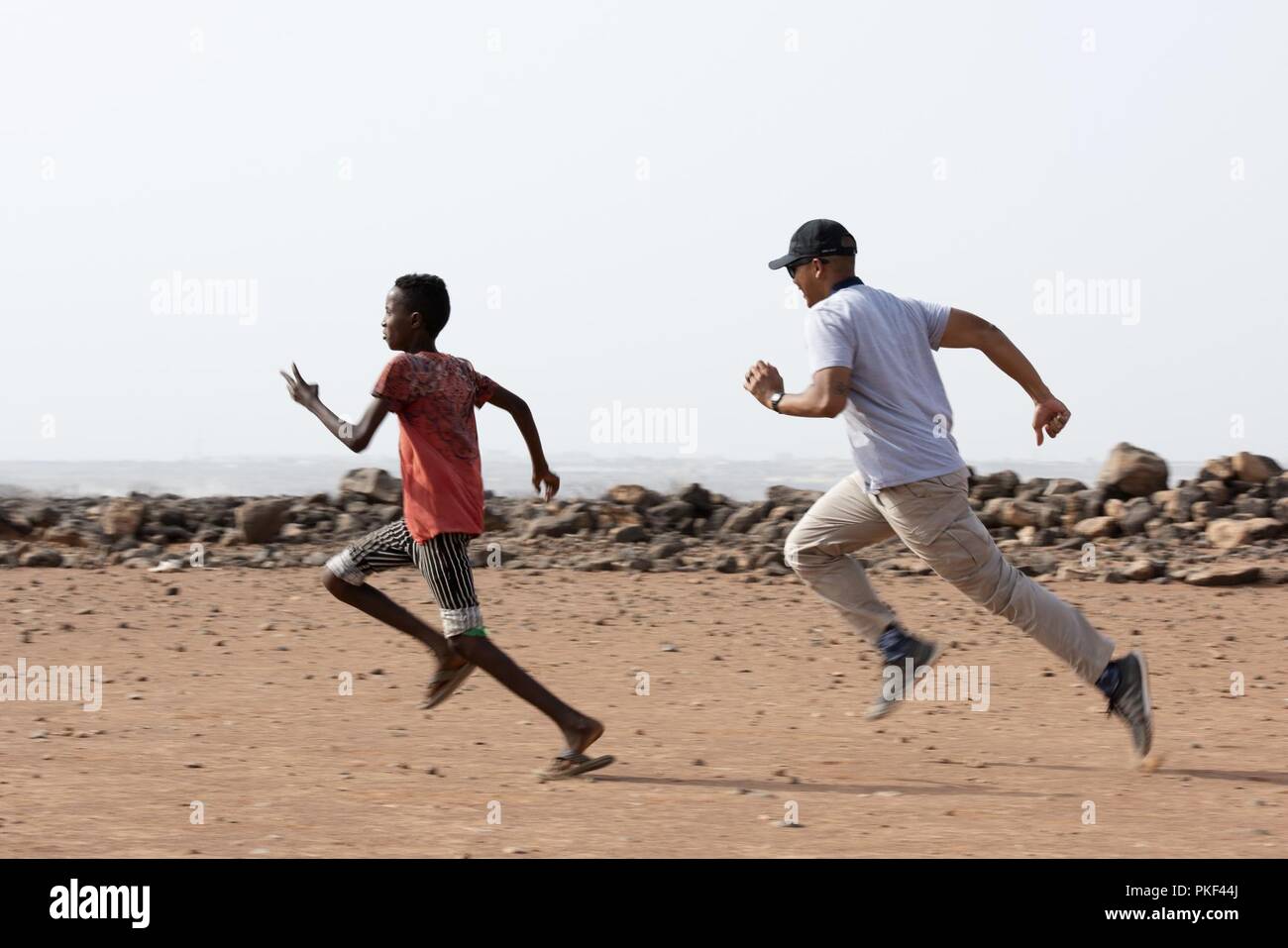 U.S. Air Force 1er lieutenant Darren Domingo, officier responsable, Caméra de combat, affecté à la Force opérationnelle interarmées - Corne de l'Afrique, des courses avec un enfant du village local à l'extérieur du village de Chebelley, Djibouti, 3 août 2018. Domingo a été l'un des 30 membres de participer à une activité de sensibilisation organisée par le 404e Bataillon des affaires civiles. Banque D'Images