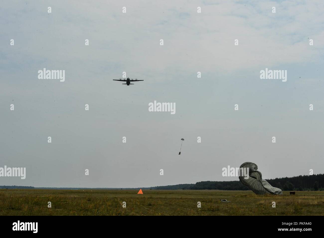Un U.S. Air Force C-130J Super Hercules survole une zone de chute comme fret forfaits livraison descendre, sur la base aérienne de Powidz, Pologne, 9 août, 2018. Les aviateurs polonais et américains ont célébré leur partenariat avec un concours de rodéo de l'aérospatiale. Banque D'Images
