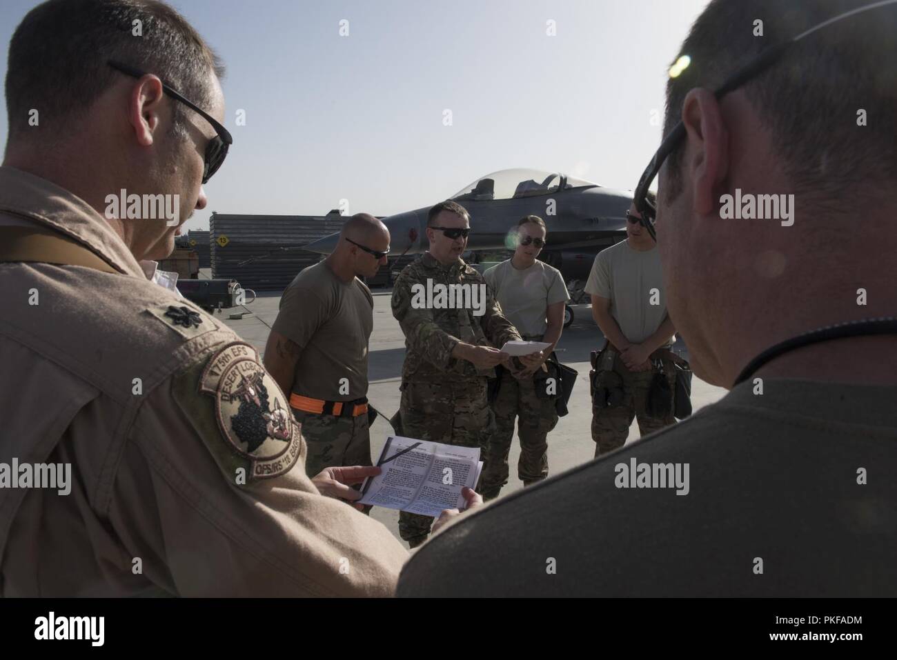 Aviateurs de la 455 e Escadre expéditionnaire aérienne (EEFA) se rassemblent autour de réciter une prière sur la ligne de vol à l'aérodrome de Bagram, en Afghanistan, le 10 août 2018. La prière a été écrit pour l'aéronef et les aviateurs qui fonctionnent et de les entretenir. L'événement était organisé par la 455 e Corps d'aumôniers de l'AEW qui sont chargés de fournir des soins pastoraux ministère et des conseils à ceux de la foi et ceux de non-foi tout affecté à la 455 e AEW. Banque D'Images