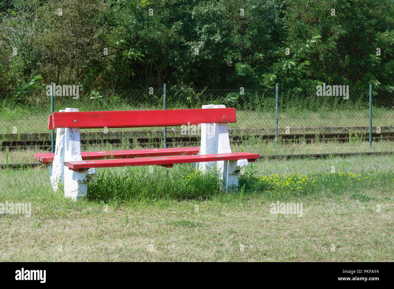 Banc rouge et jaune fleurs à une gare rurale en Europe orientale, la Hongrie Banque D'Images