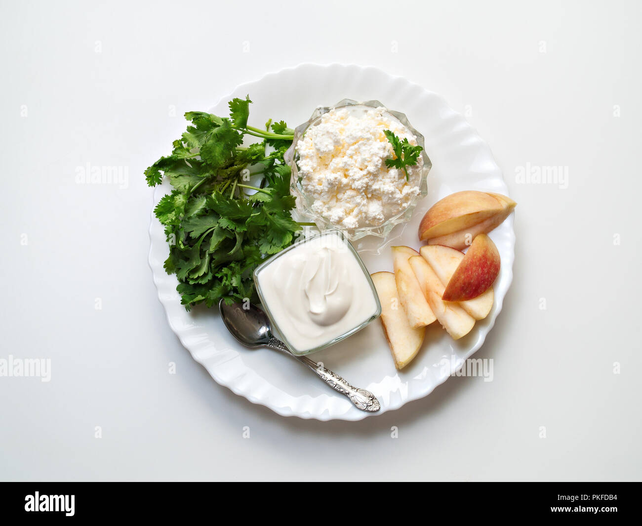 Le fromage blanc et la crème sure dans des plaques de verre se trouve sur une plaque blanche avec la coriandre vert et de tranches de pomme fraîche Banque D'Images
