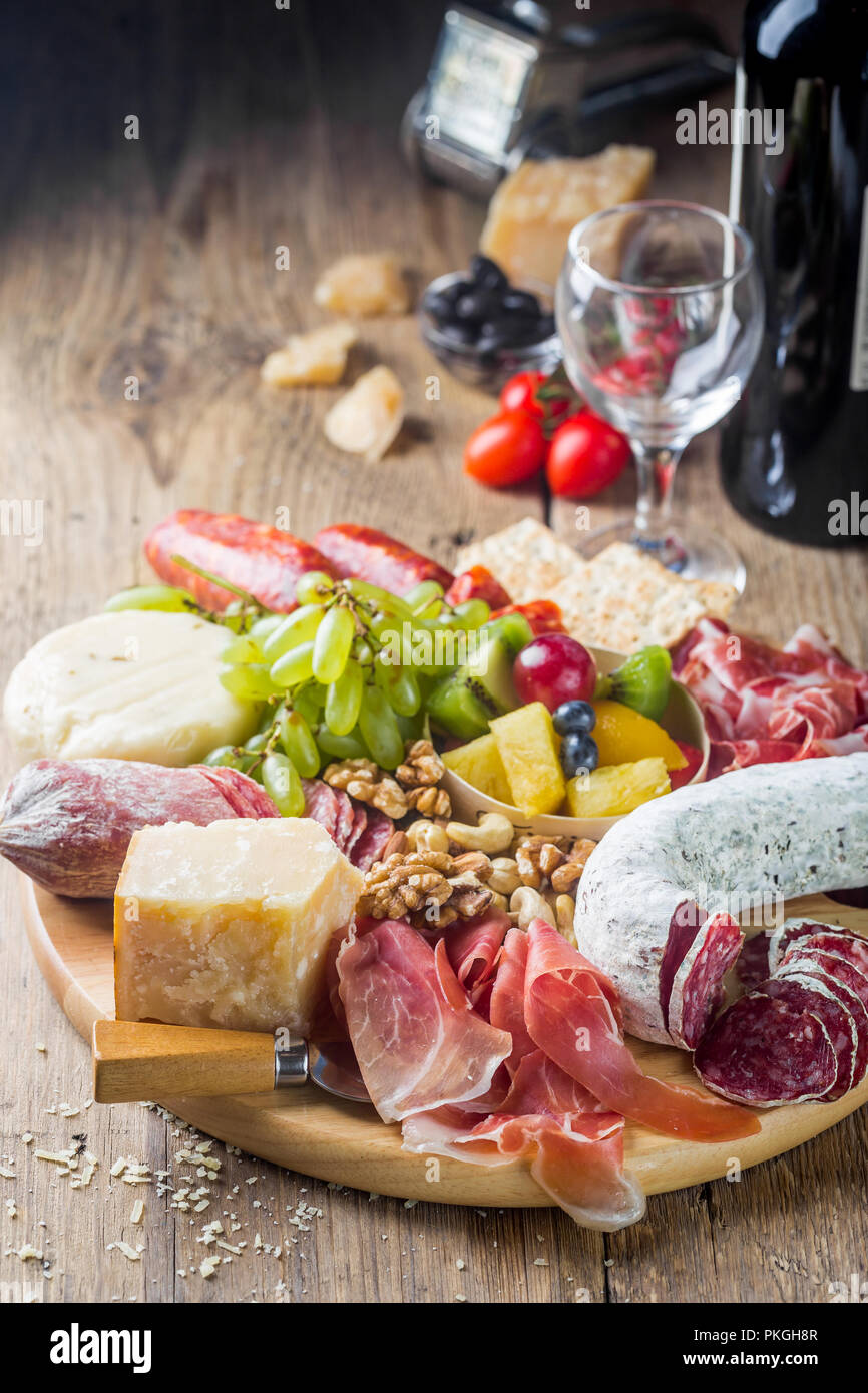 Mélange de différentes collations et des apéritifs. Des tapas espagnoles ou vin italien situé sur une plaque de bois. Bar à Tapas. Les noix, les olives, saucisses, fromage, jambon, tomates Banque D'Images