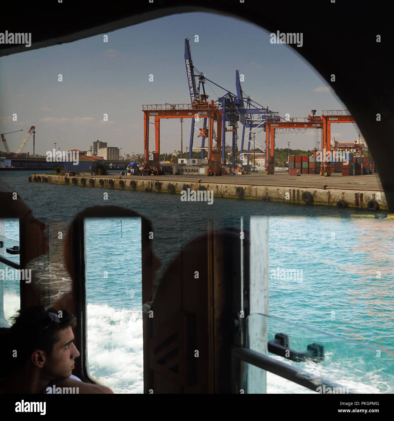 Istanbul, Turquie - 25 août 2018 : un jeune homme regardant la vue sur le port de Haydarpasa. Il y a des belles réflexions sur fenêtre. Banque D'Images