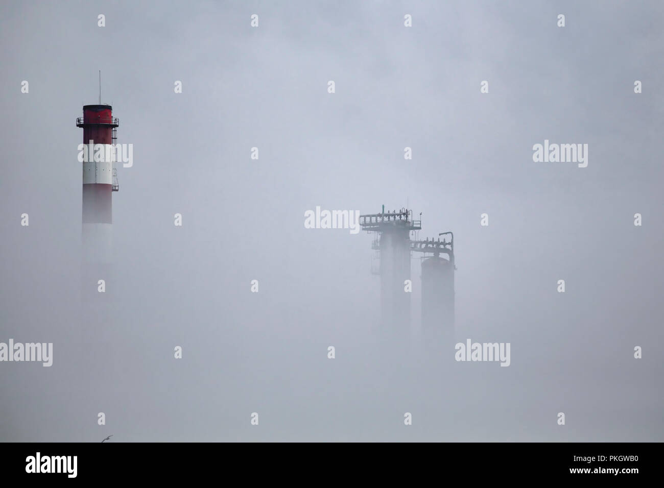 Raffinerie de pétrole et de cheminée semi losted tours dans le brouillard Banque D'Images