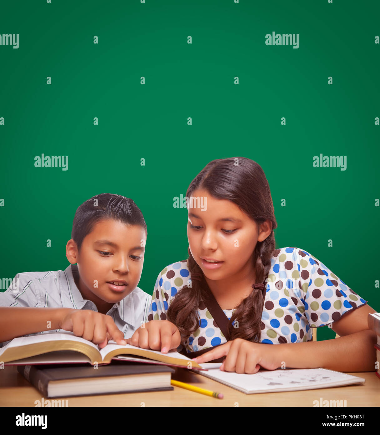 Chalk Board vierge derrière Hispanic Boy and Girl s'amusant d'étudier ensemble. Banque D'Images