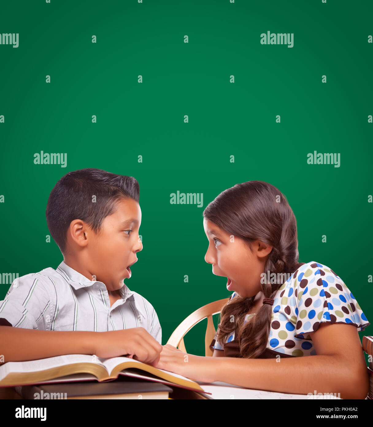 Chalk Board vierge derrière Hispanic Boy and Girl s'amusant d'étudier ensemble. Banque D'Images
