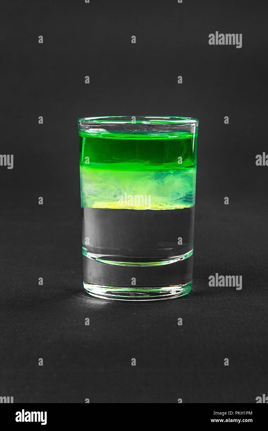 Cocktail en couches multicolores, avec verre transparent et verre de couleur avec le goût de menthe, banane, citron, absinthe, alcoolique, isolée, vue latérale Banque D'Images