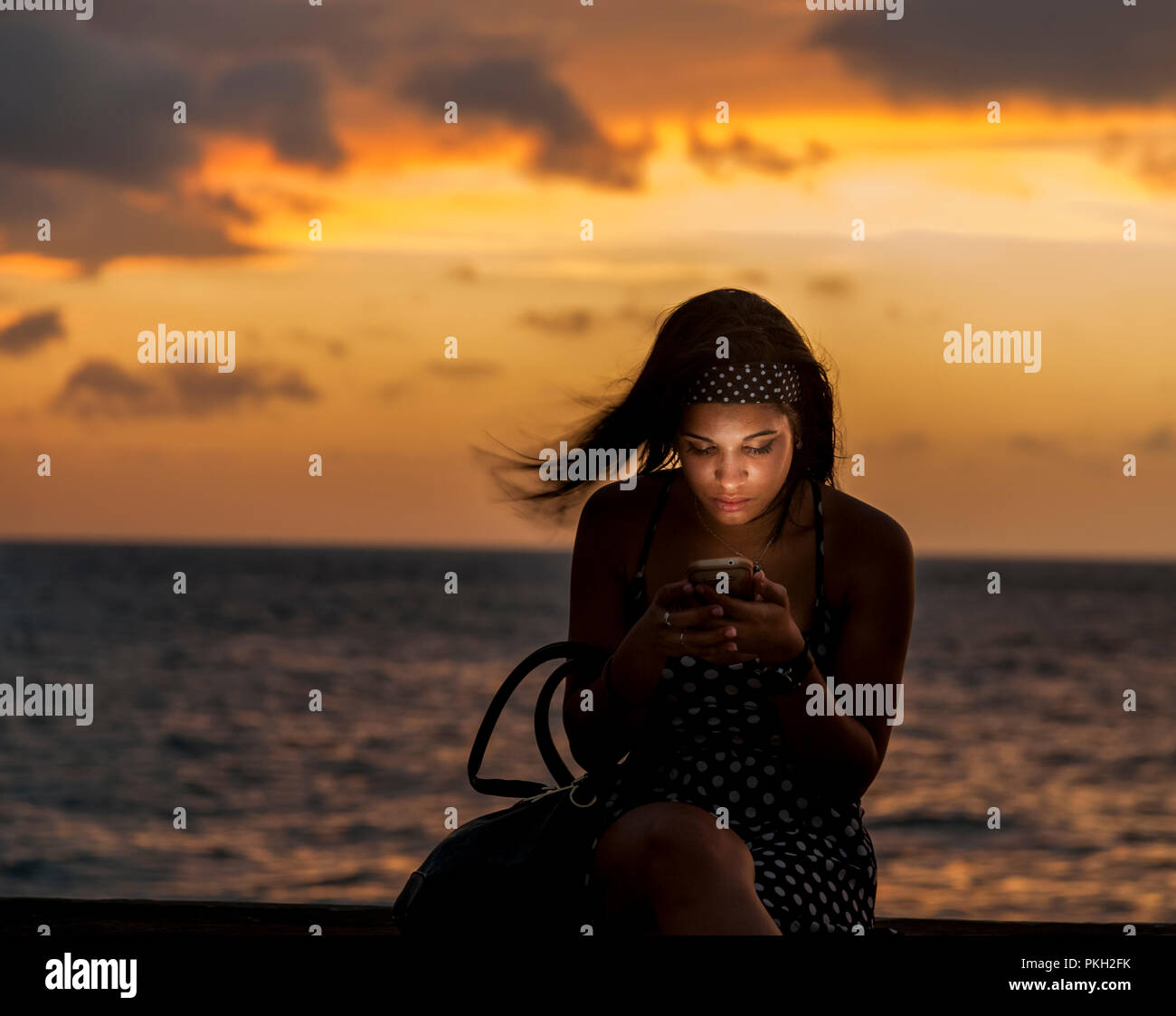 La Havane, Cuba. 22 juillet 2017 Maria Sotolongo surfe sur internet tout en restant assis sur le mur en Melacon La Havane Cuba. -Crédit David Creedon / Alamy Banque D'Images