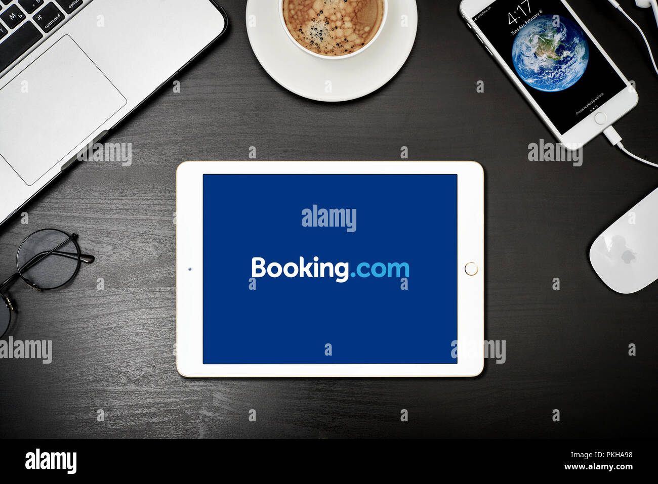 Kiev, Ukraine - Février 6, 2018 : Apple iPad or avec Booking.com app sur l'écran de bureau noir avec MacBook et iPhone, vue du dessus. Booking.com est Banque D'Images