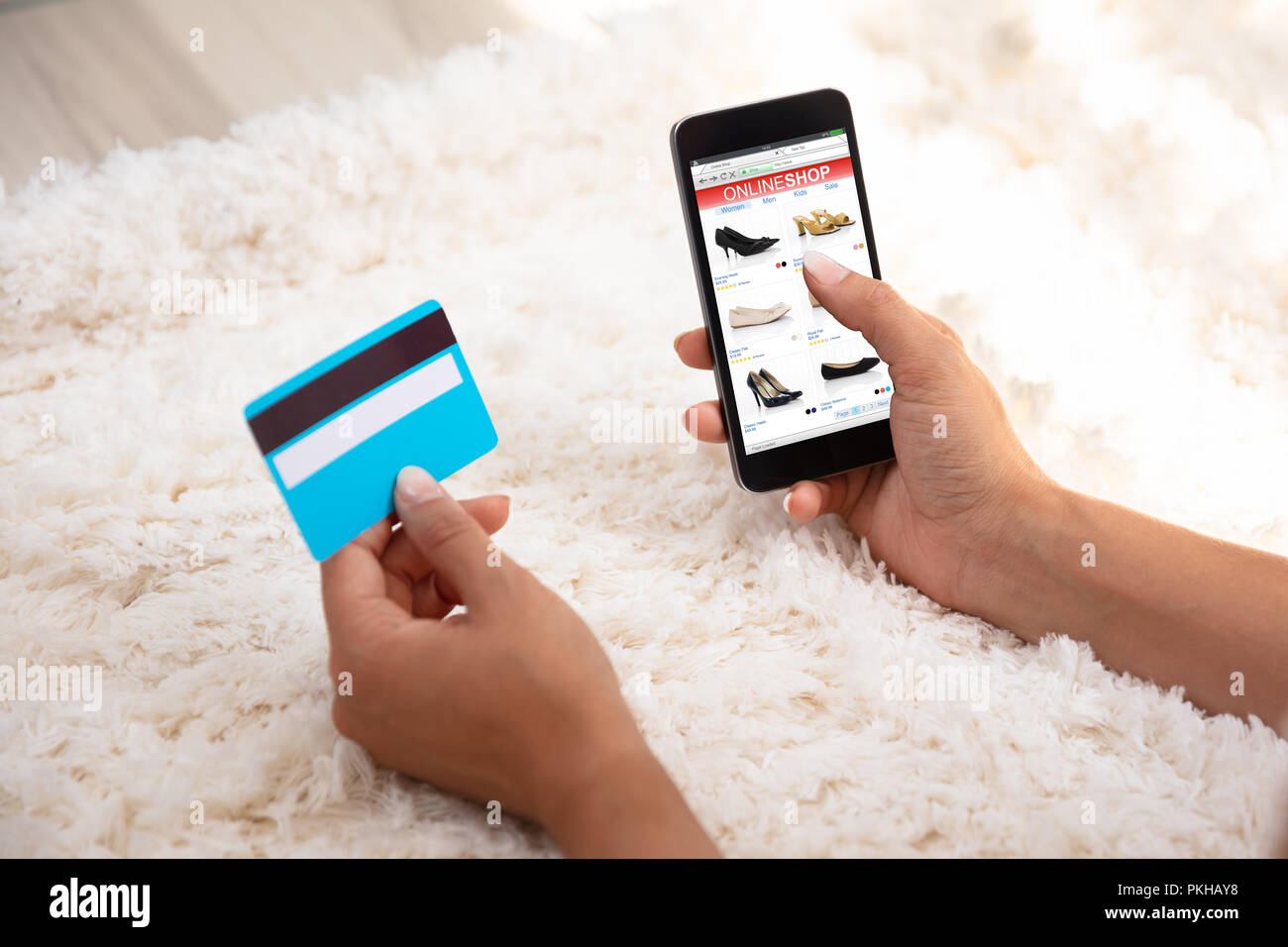La main de femme à l'aide de carte de crédit pour des achats en ligne sur sur un tapis cellulaire Banque D'Images La main de femme à l'aide de carte de crédit pour des achats en ligne sur sur un tapis cellulaire Banque D'Images