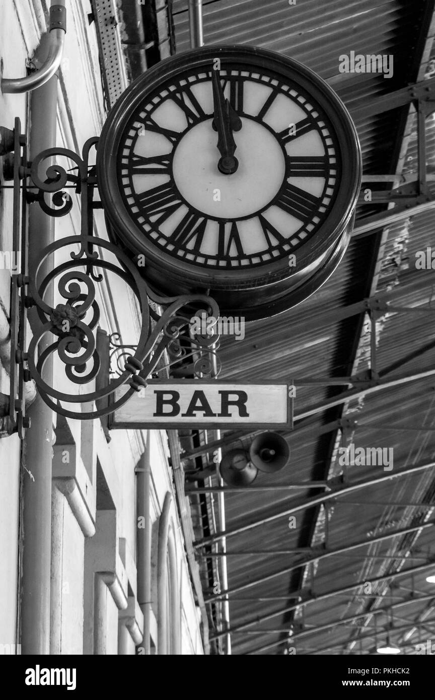Style ancienne horloge de plus un signe dans la zone de fréquentation d'une gare. Le noir et blanc Banque D'Images