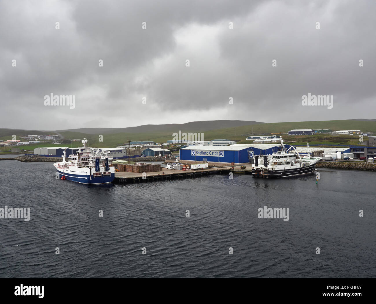 Les bateaux de pêche sont amarrés le Shetland prendre du poisson usine quai sur une journée pluvieuse d'août humide dans les îles Shetland. Lerwick, Ecosse, Royaume-Uni. Banque D'Images